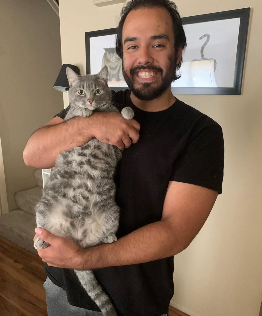 Zach, owner of cat, and Biscuit posing together. 