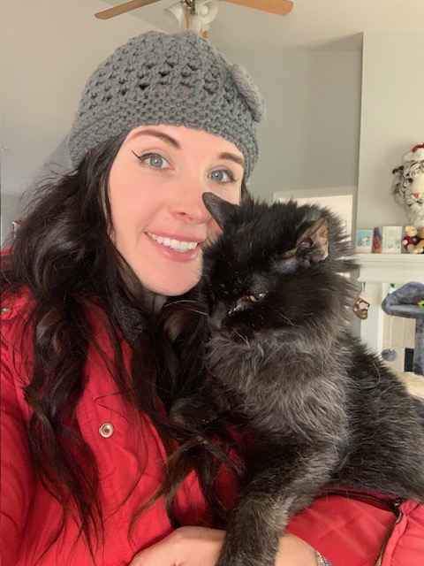 Maria, cat owner, holding her Midnight, a black cat, and smiling while Midnight looks downward. 